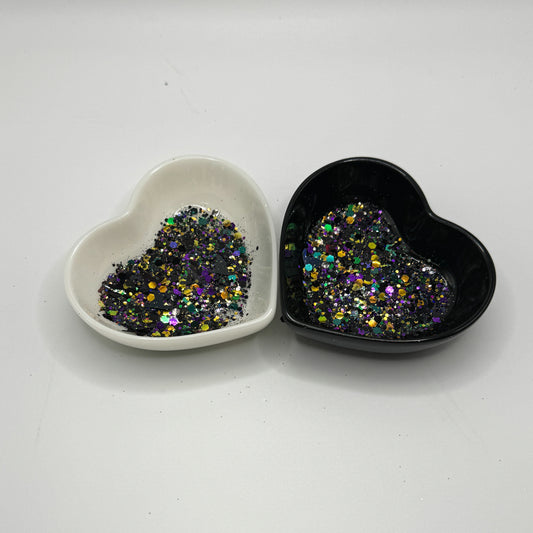 Two heart shaped containers, one black, one white, containing a Black/Green/Hunter Green/Purple/Orange chunky glitter mix with hexagons and witch hats.