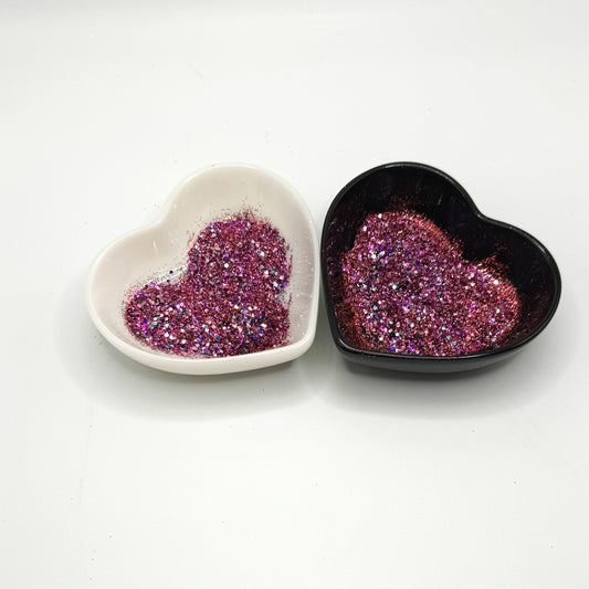A white and black heart shaped dish showing a Pink/Red/Blue/Purple medium glitter mix.