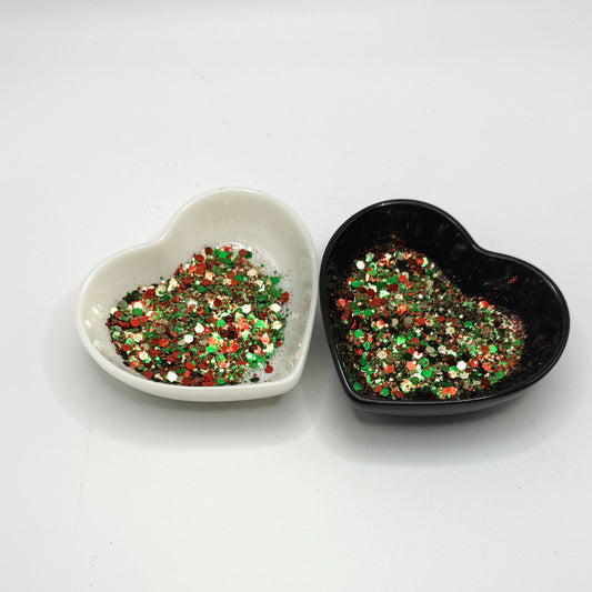 Two heart shaped containers, one black, one white, containing a Red/Green/Silver chunky glitter mix.