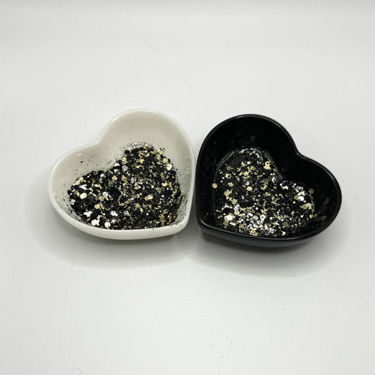 Two heart shaped containers, one black, one white, containing a Black/Gold chunky glitter mix.