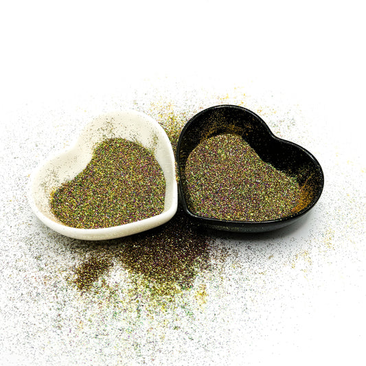 Two heart-shaped containers of glitter, one black and the other white, both showing an extra fine, green, purple glitter mix