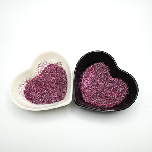 Two heart-shaped dishes containing extra fine purple glitter, displayed on a white background.