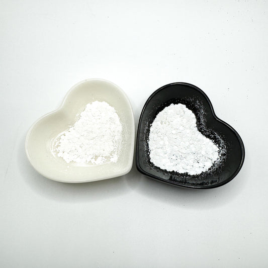 Two heart shaped containers, one black, one white, containing a White chunky glitter mix.
