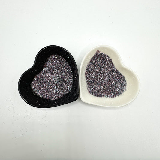 Two heart-shaped containers of glitter, one black and the other white, both showing an extra fine, multicoloured glitter mix