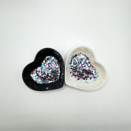 Two heart shaped containers, one black, one white, containing a Light Teal/Light Purple/Light Pink chunky glitter mix.
