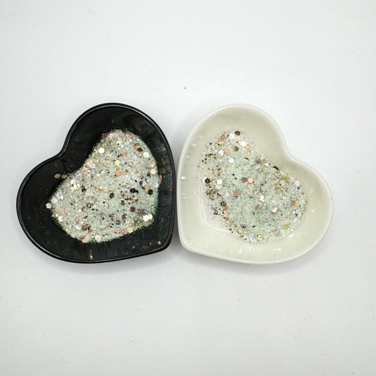 Two heart shaped containers, one black, one white, containing a Aqua/Rose Gold/Gold/Silver chunky glitter mix.