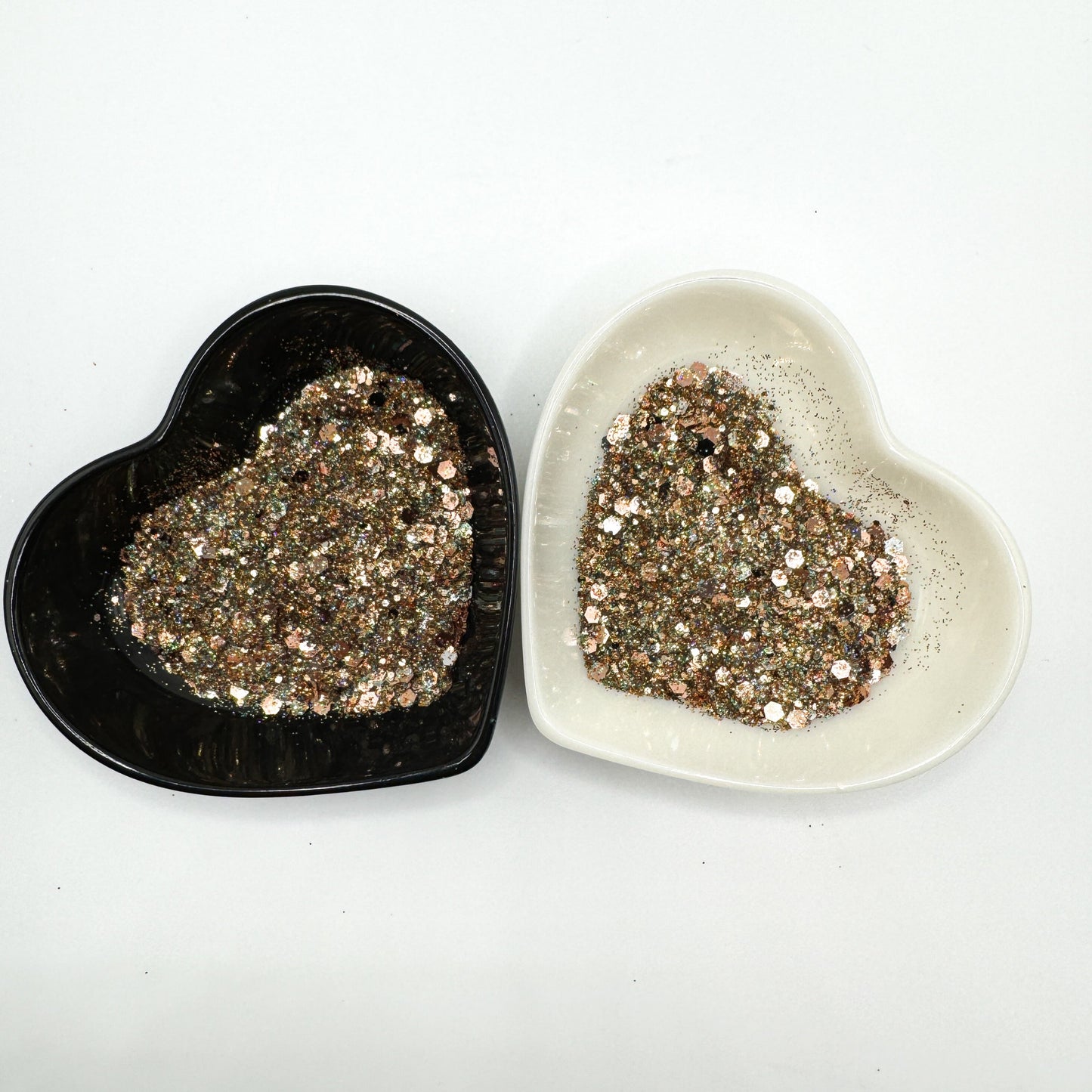 Two heart shaped containers, one black, one white, containing a Light Teal/Black/Silver/Rose Gold chunky glitter mix.