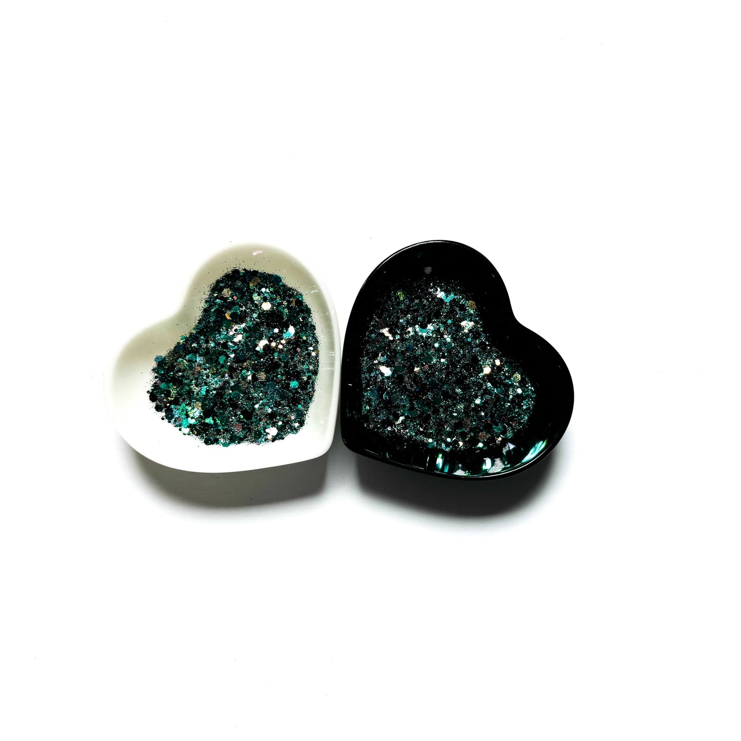 Two heart shaped containers, one black, one white, containing a Teal/Black/White chunky glitter mix.