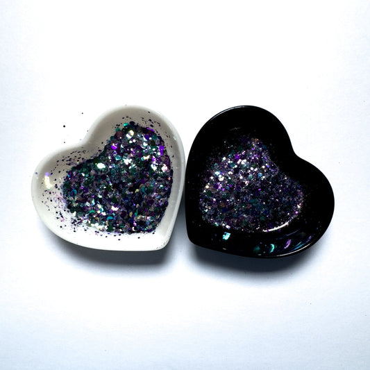 Two heart shaped containers, one black, one white, containing a Purple/Blue/Green/White chunky glitter mix.