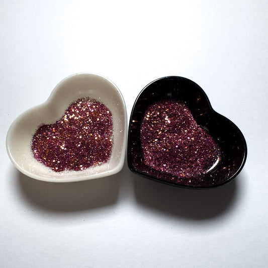 A white and black heart shaped dish showing a Purple/Orange/Gold/Rose medium glitter mix.