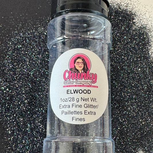 A clear plastic shaker bottle labeled 'Elwood' containing extra fine glitter, with a black lid and a label featuring a pink logo and white text.