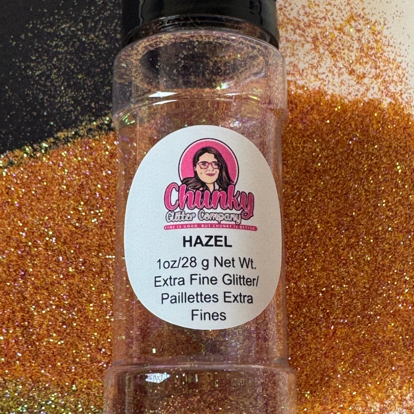 A clear plastic bottle with a black lid, labeled 'Chunky Glitter Company', containing extra fine glitter orange glitter mix with a scattered glitter background.
