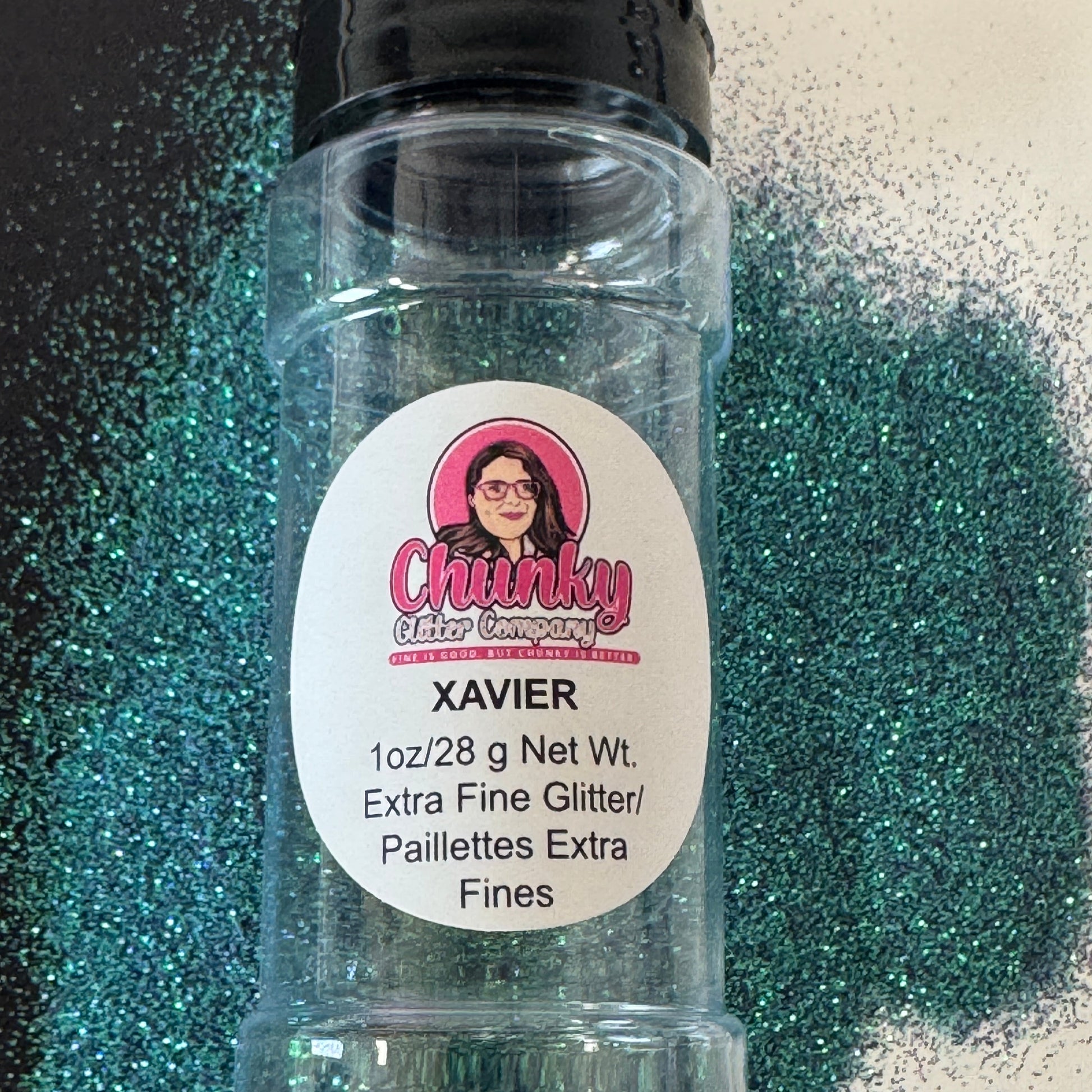 A clear plastic bottle with a black lid, labeled 'XAVIER', containing extra fine green, blue, purple glitter. The label shows the brand 'Chunky glitter company' and mentions the product is a premium, non-toxic, solvent resistant polyester glitter.