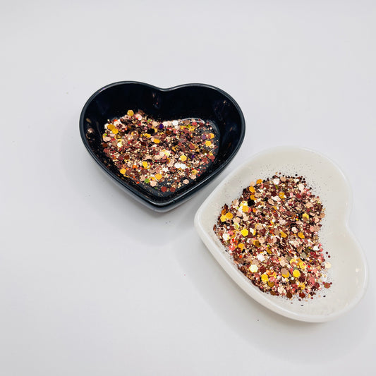 Two heart shaped containers, one black, one white, containing a Brown/Rose Gold chunky glitter mix.