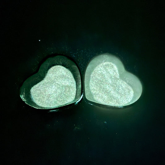 Two heart-shaped containers filled with glow-in-the-dark glitter.