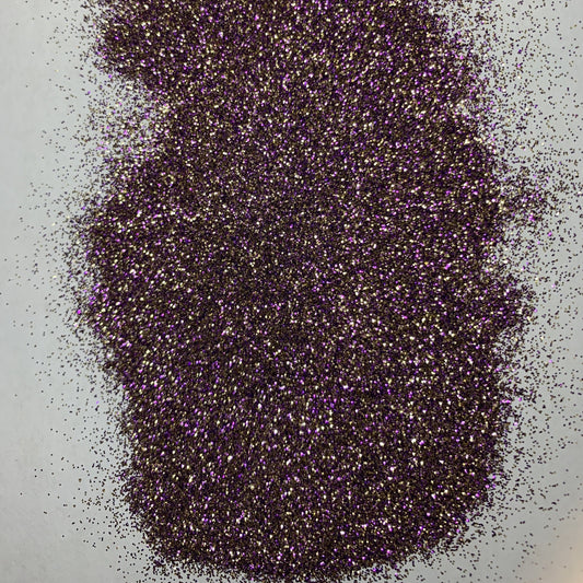 A close-up of purple and gold glitter, indicating a sparkling or shimmering effect, typically used for crafts or decoration.