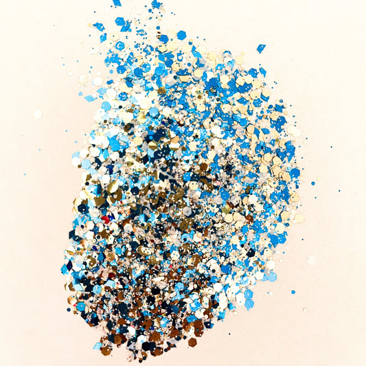 A pile of blue and gold, chunky glitter mix spread on a white surface.