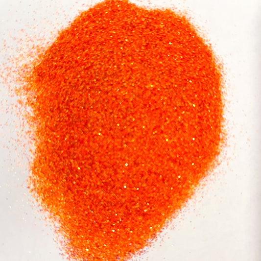A pile of orange, extra fine glitter spread on a white surface.