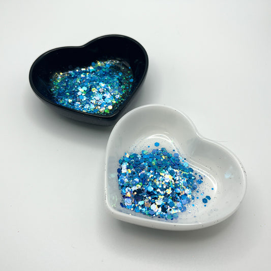 Two heart shaped containers, one black, one white, containing a Blue/White chunky glitter mix.