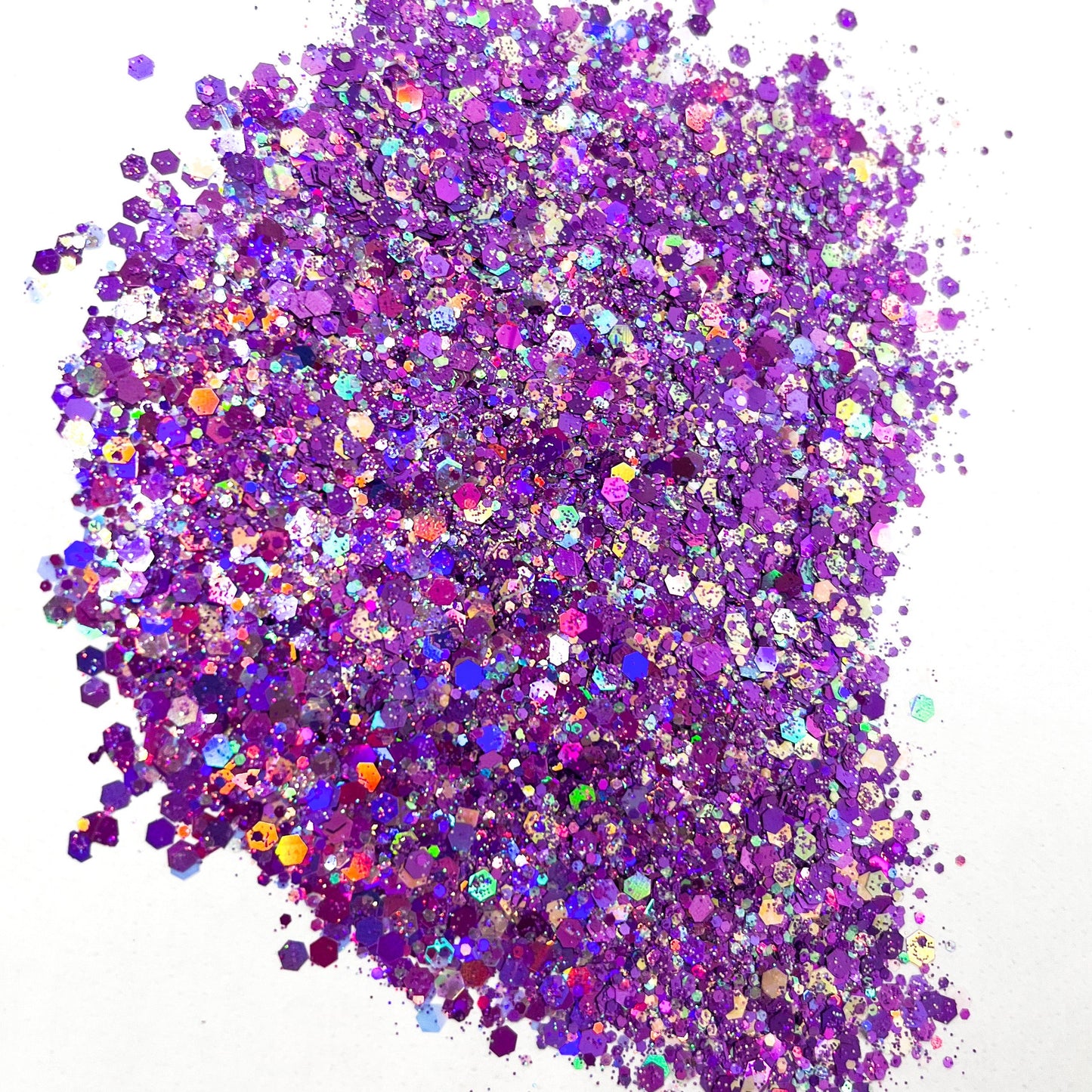 A pile of purple holographic chunky glitter on a white background.
