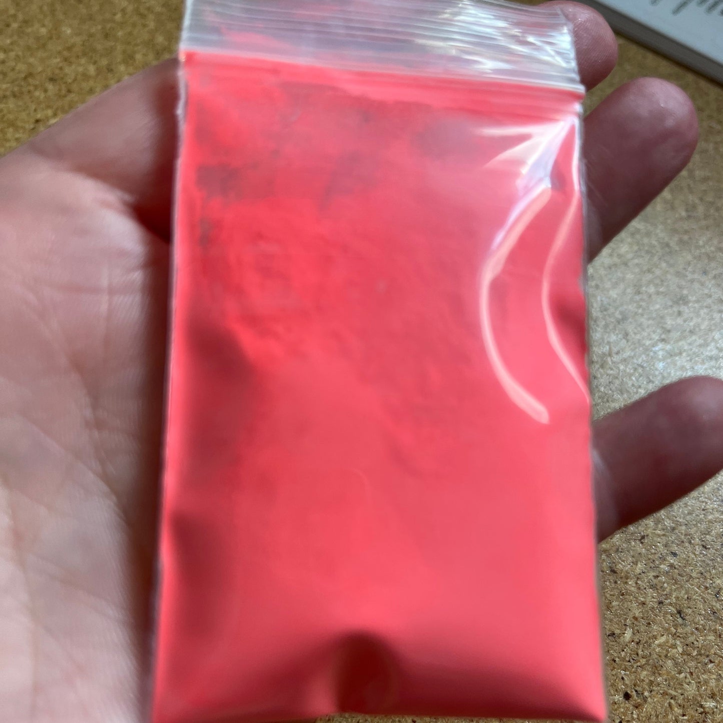 A bag of orange glow in the dak powder in an open palm.