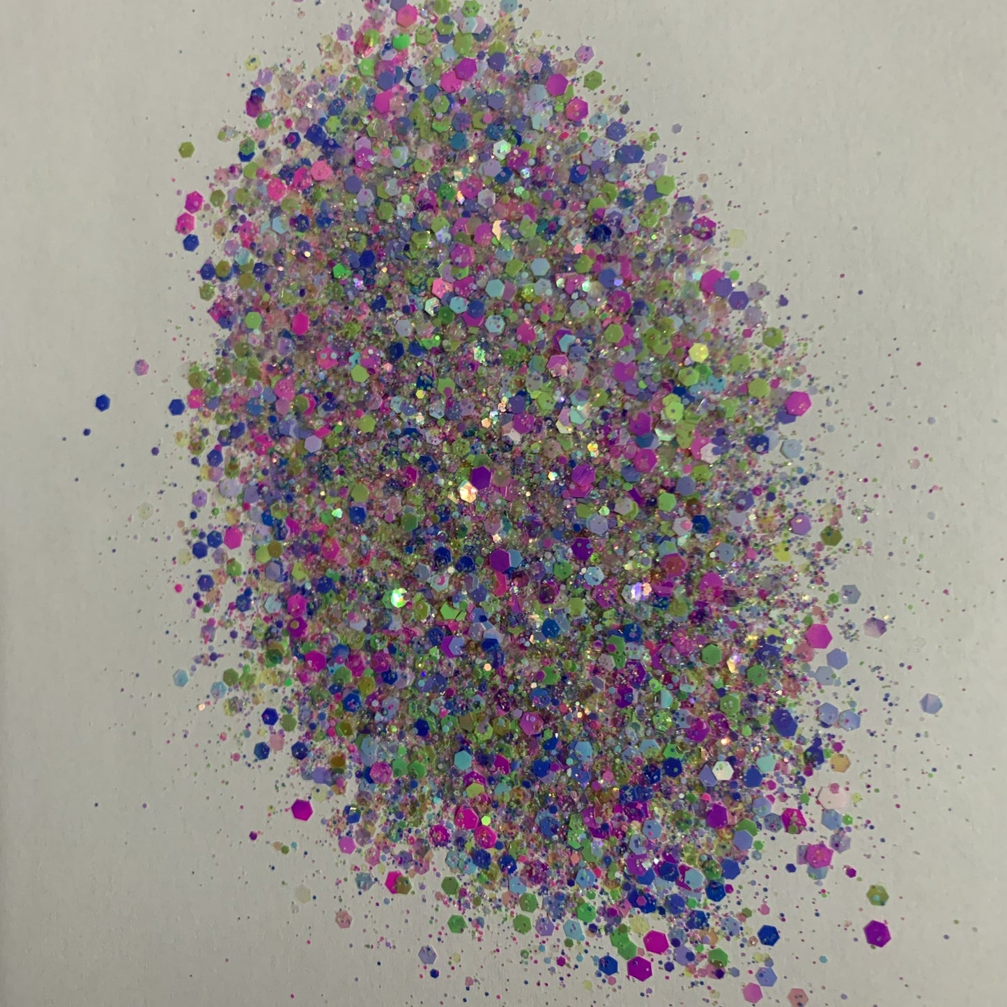 A colorful mixture of various sizes of glitter particles, including pink, green, blue, and silver colors.