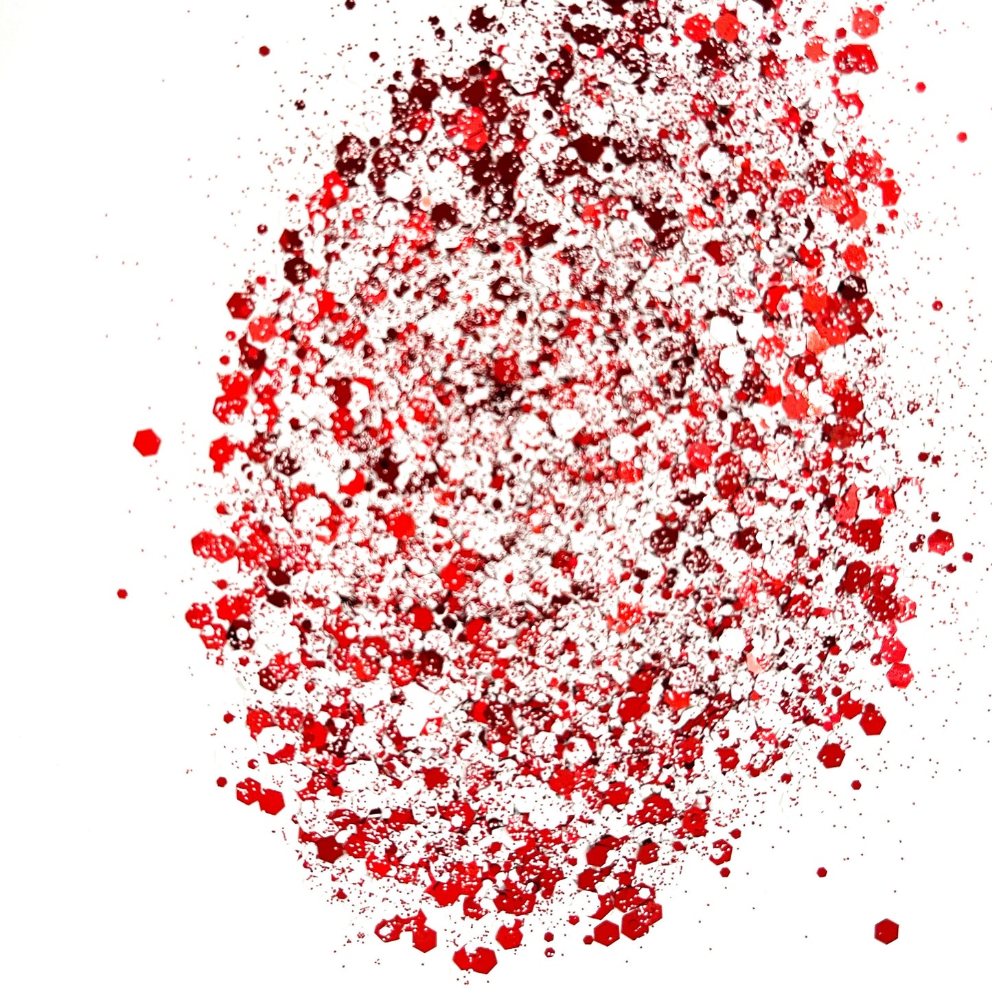 A close-up image of a red and white chunky mix glitter, displaying various sizes of particles against a white background.