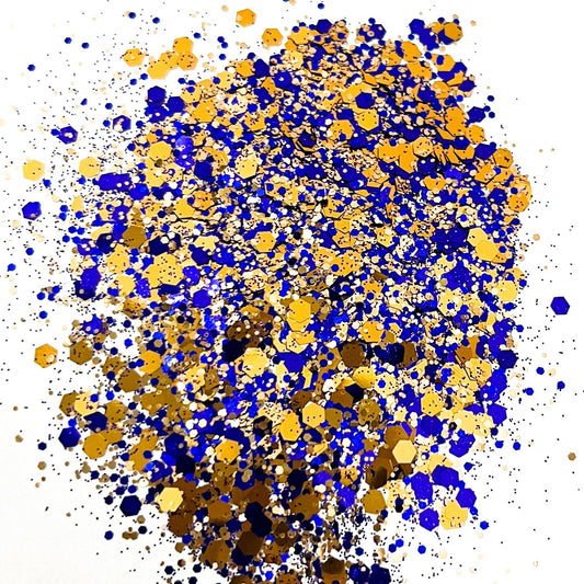 A pile of mixed colours of chunky glitter, including Indigo/Bronze, on a white background.