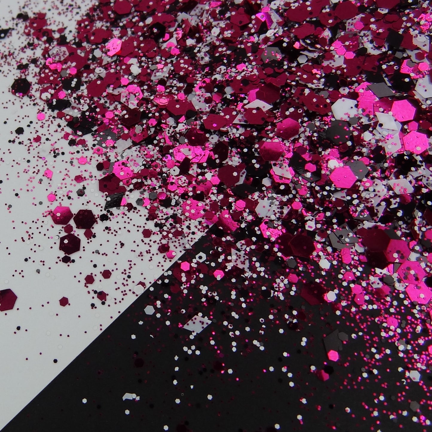 A pink, black and white chunky glitter mix spread out on a black and white background.