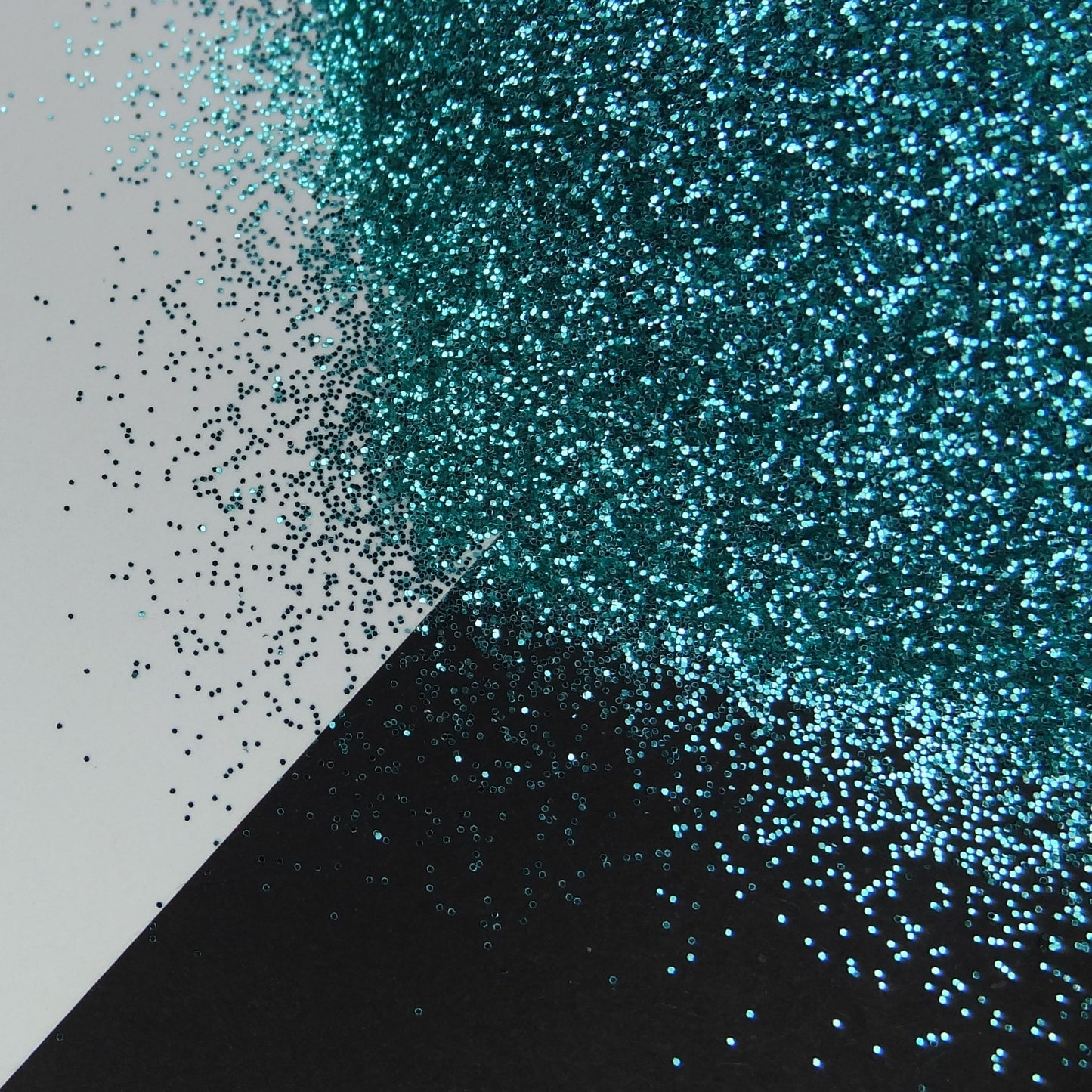 A light turquoise extra fine glitter spread out on a black and white background.