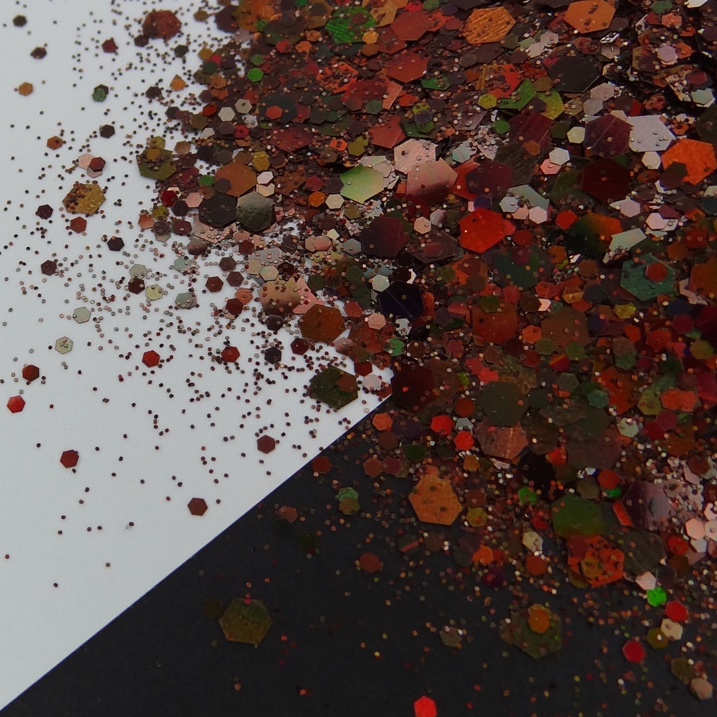 A brown holographic chunky glitter mix spread out on a black and white background.