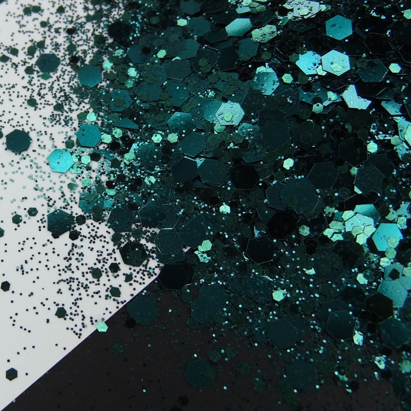 A pile of hunter green chunky glitter on a white and black background.