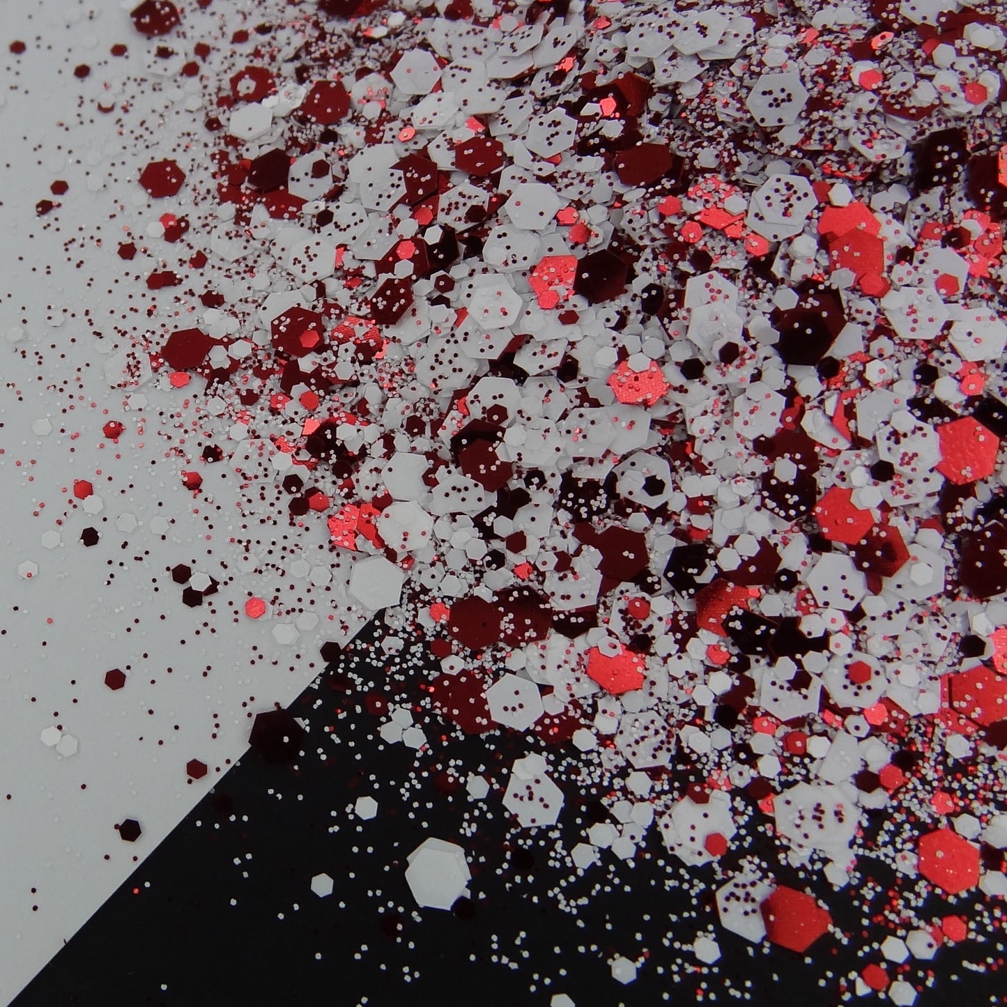 A red and while chunky glitter mix spread out on a black and white background.