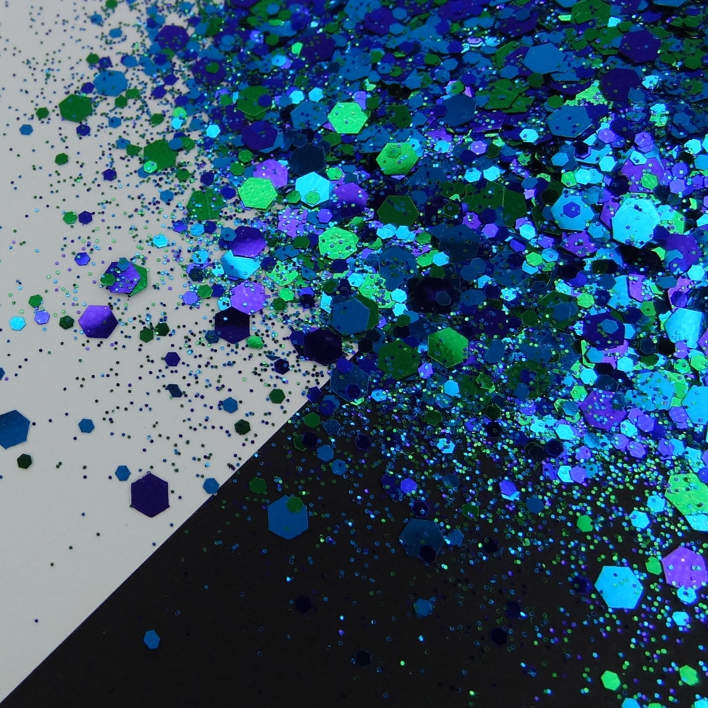 A blue and green chunky glitter mix spread out on a black and white background.