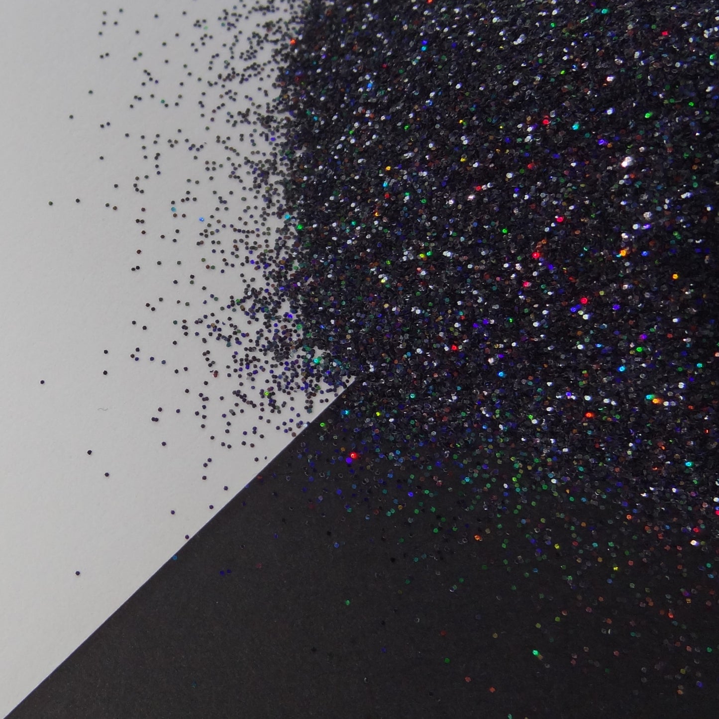 A black holographic extra fine glitter spread out on a black and white background.