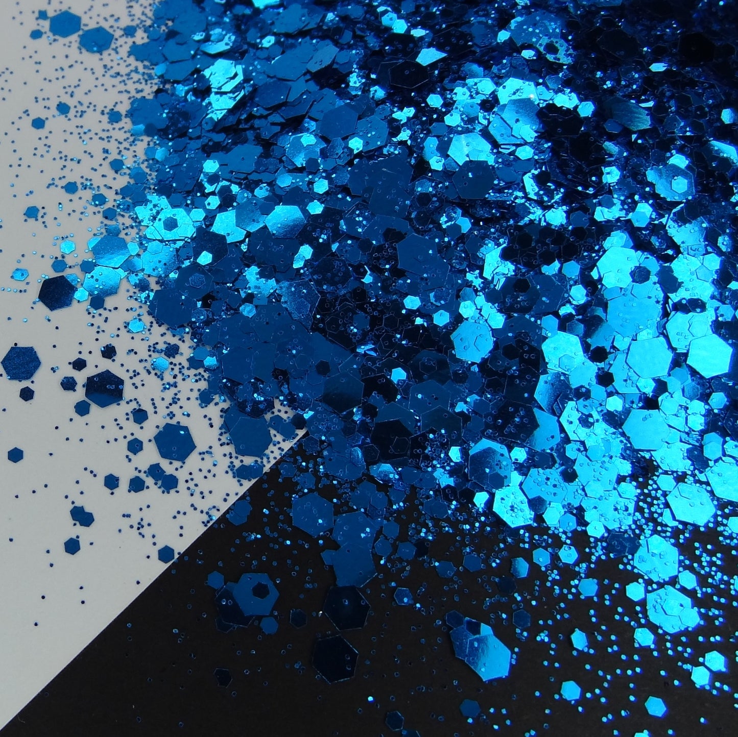 A pile of royal blue chunky glitter on a black and white background.