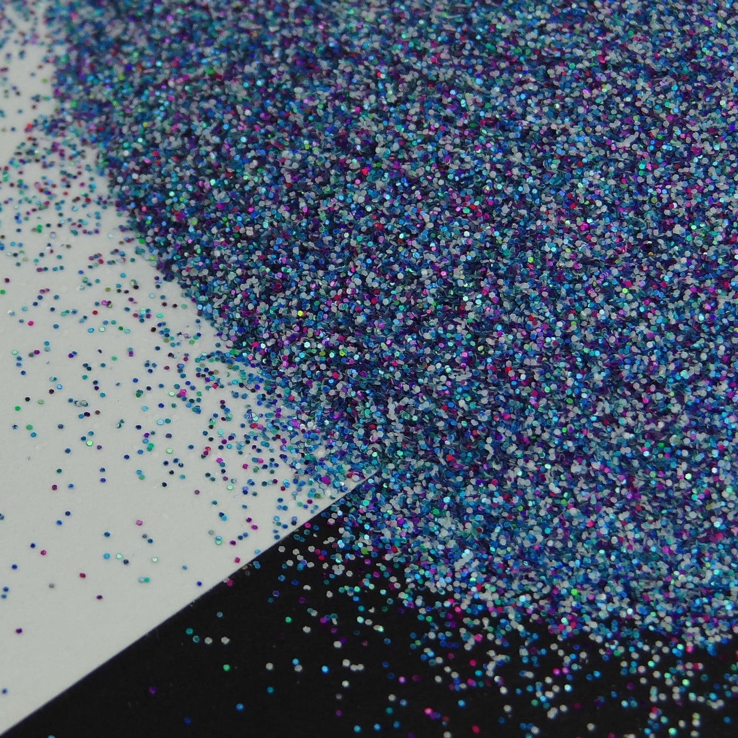 A pile of mixed colours of glitter, on a white and black background.