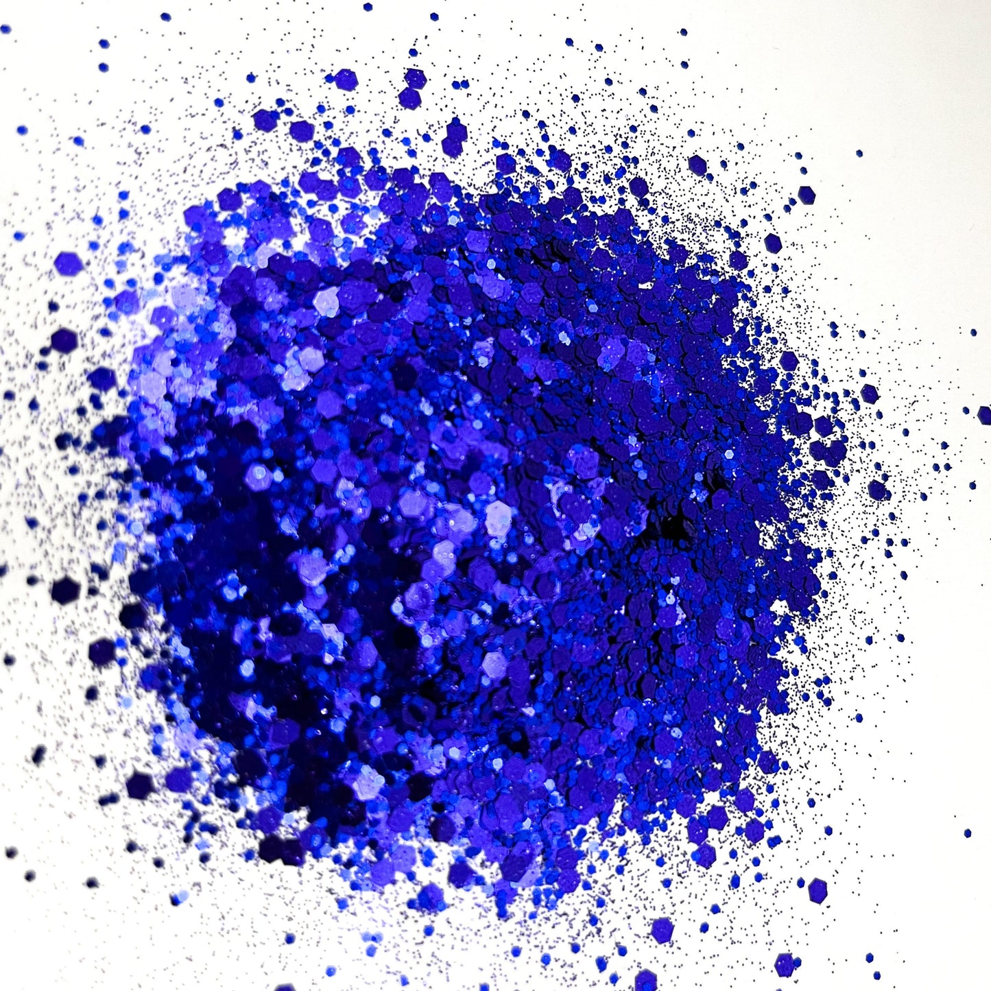 A pile of indigo chunky glitter on a white background.