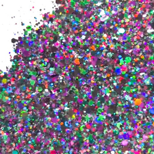 A pile of mixed colours of chunky glitter, including Hunter Green/Dark Green/Purple/Black on a white background.