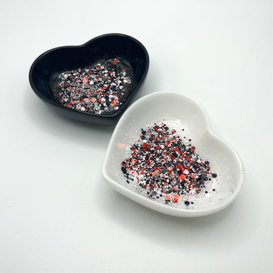 Two heart shaped containers, one black, one white, containing a Red/White/Black chunky glitter mix.