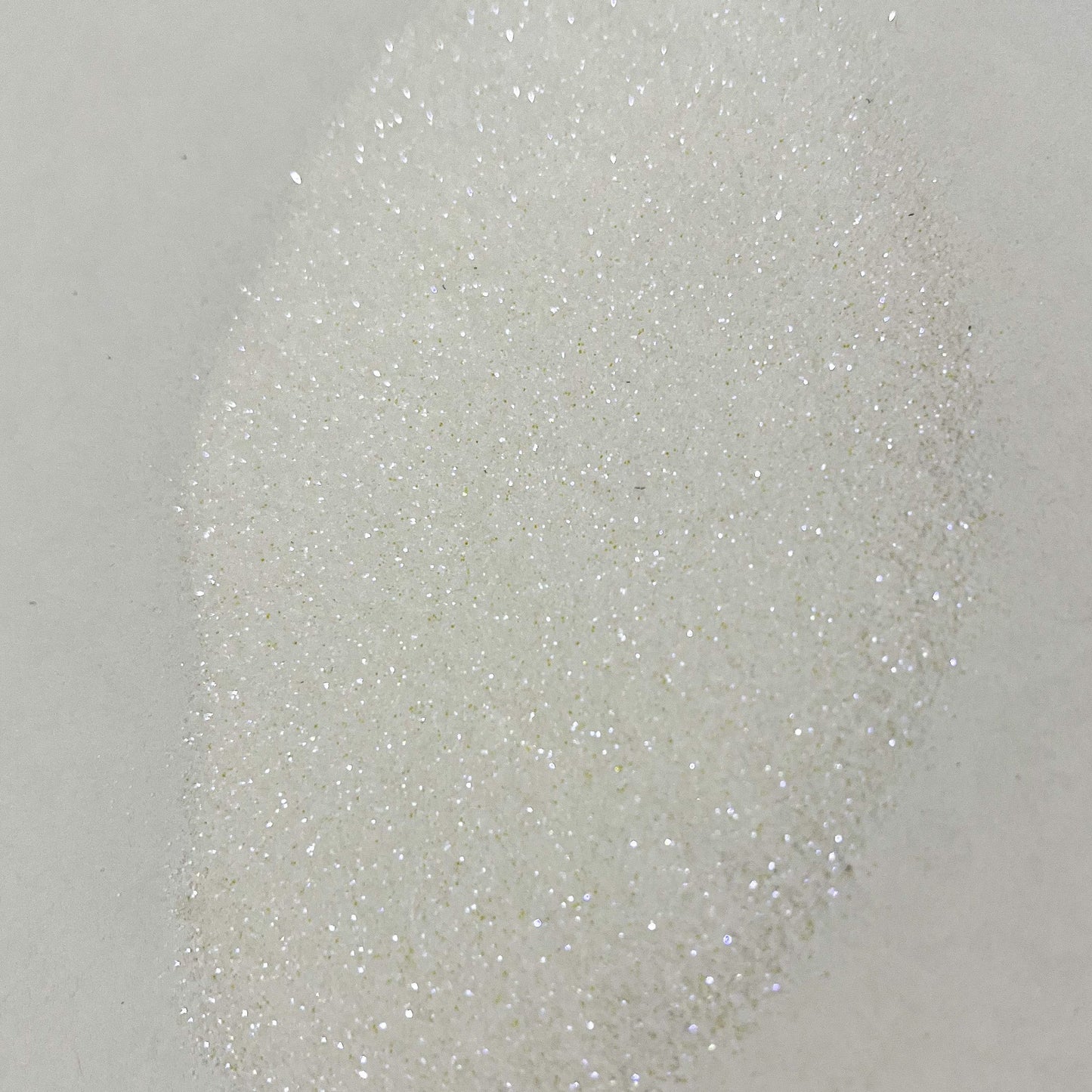 A close-up image of white polyester glitter with a sparkling appearance.