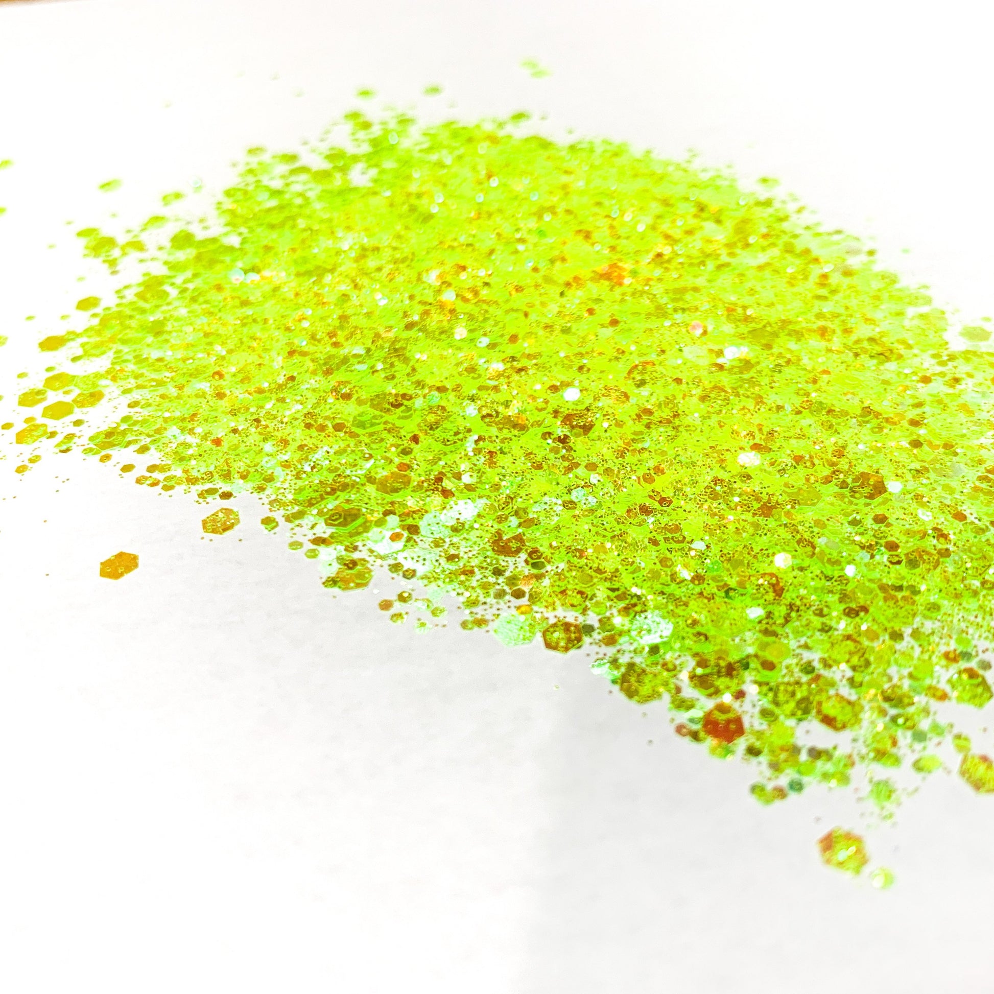 A pile of yellow chunky glitter on a white background.