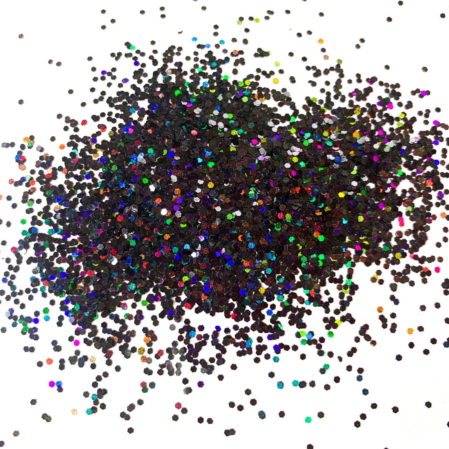 A pile of multicolored glitter particles, ranging from black to various shades of multicolor, spread out on a white background.