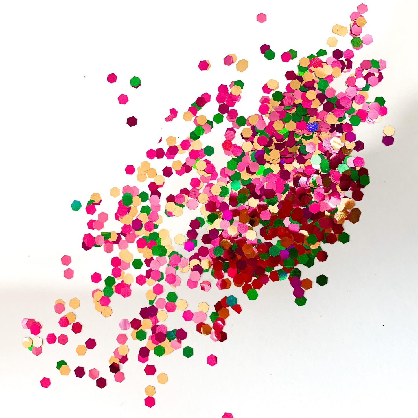 A pile of XL cut glitter in purple, green, gold and pink colours on a white background.