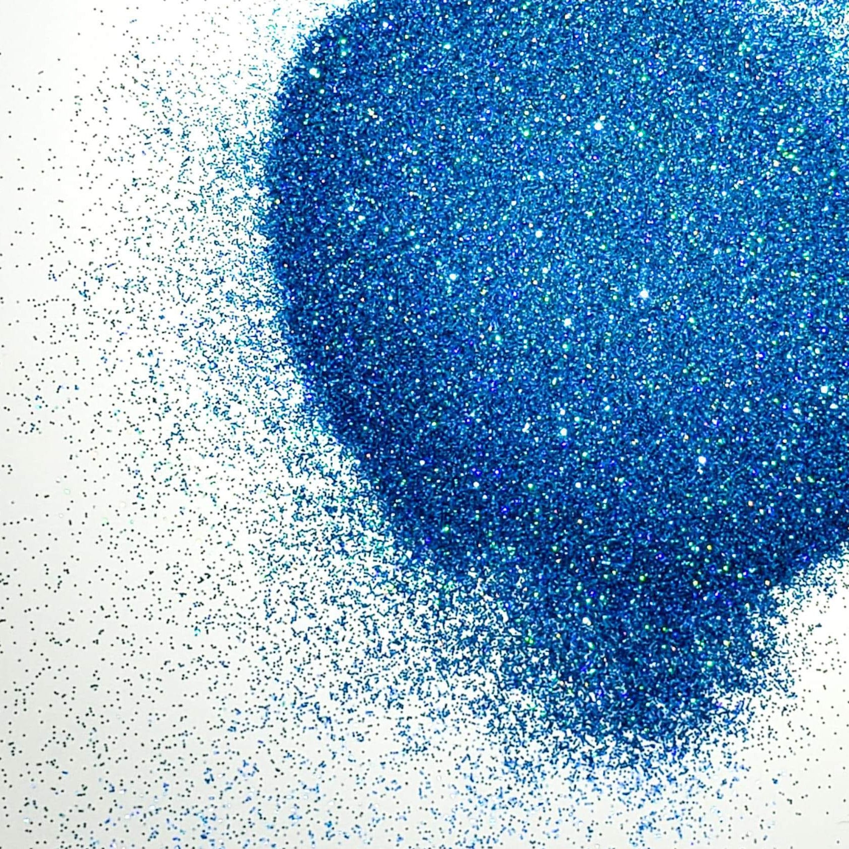 A pile of blue holographic glitter, in extra fine on a white background.