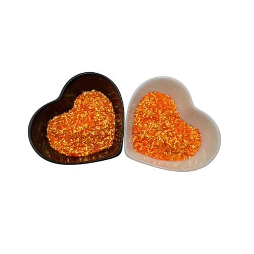 A white and black heart shaped dish showing a Orange medium glitter mix.