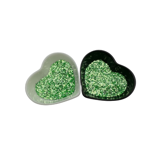 A white and black heart shaped dish showing a bright green medium glitter.