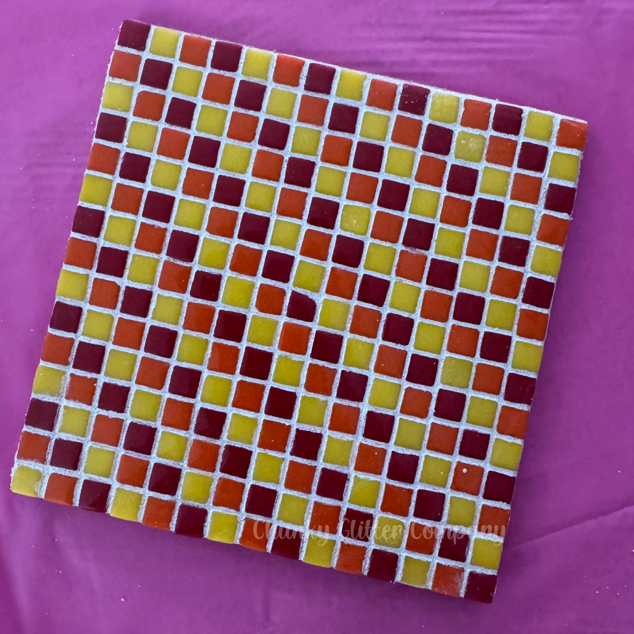 Square tile with a grid of small squares in red, yellow, and orange on a purple background