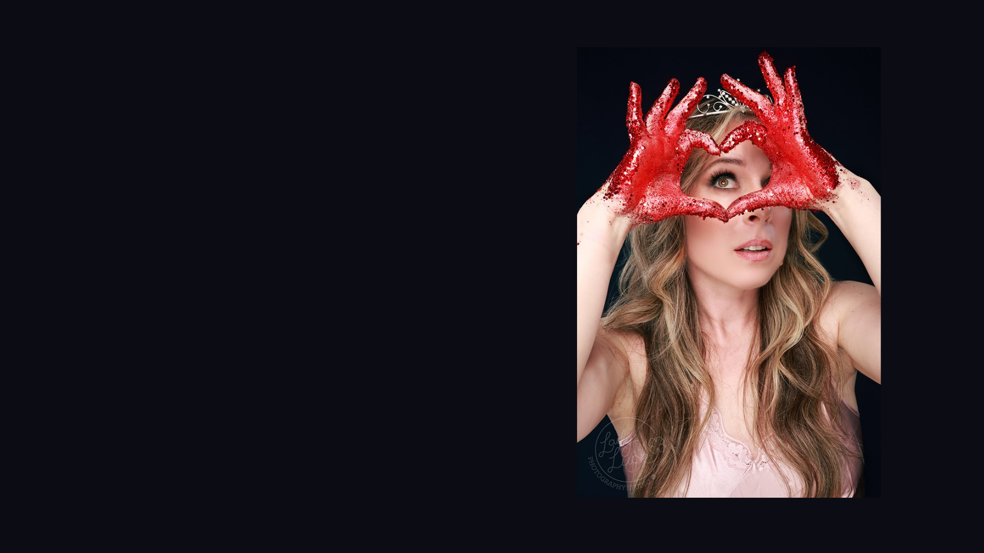 Person with red, glittered hands forming a heart shape over their face against a black background