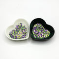Two heart shaped containers, one black, one white, containing a Green/Purple chunky glitter mix.